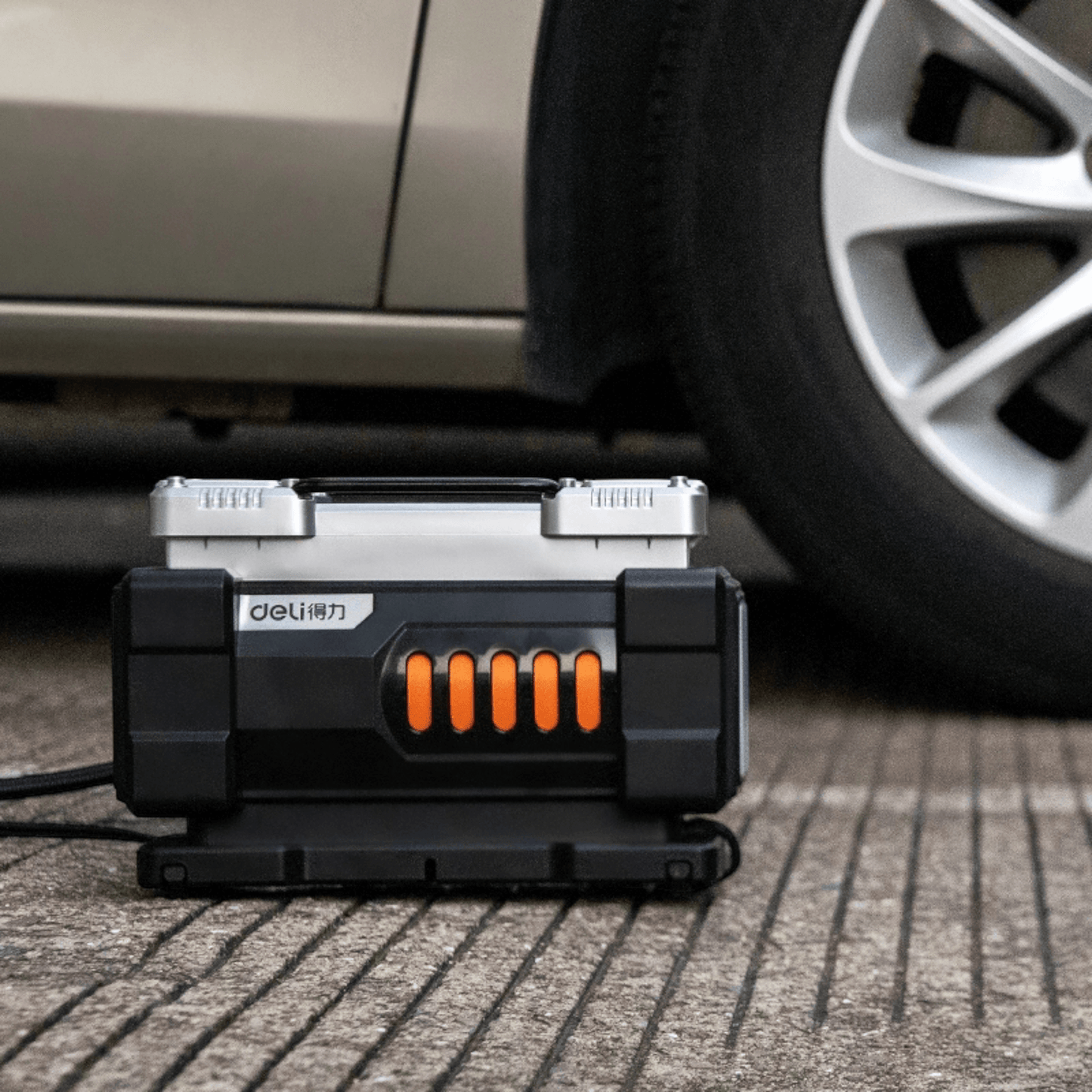 DL-TK-A1S Digital Air Compressor Pump 12V (DELI) in use beside a car wheel, showcasing compact and efficient design for tire inflation.